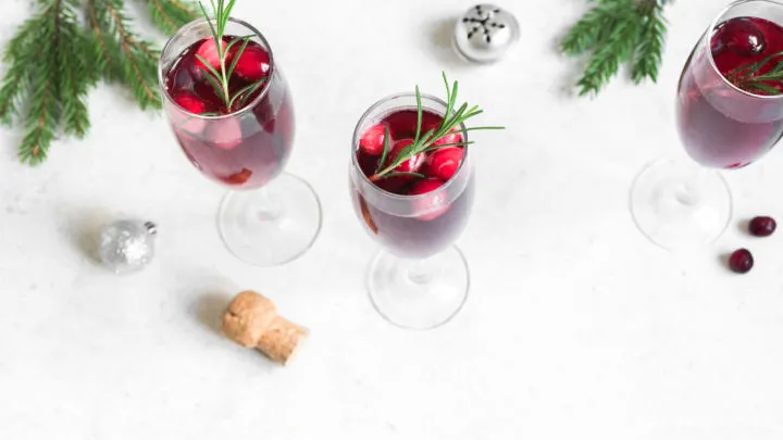 Christmas red cranberry mimosa with rosemary on white background, Cocktail with champagne for Christmas morning.